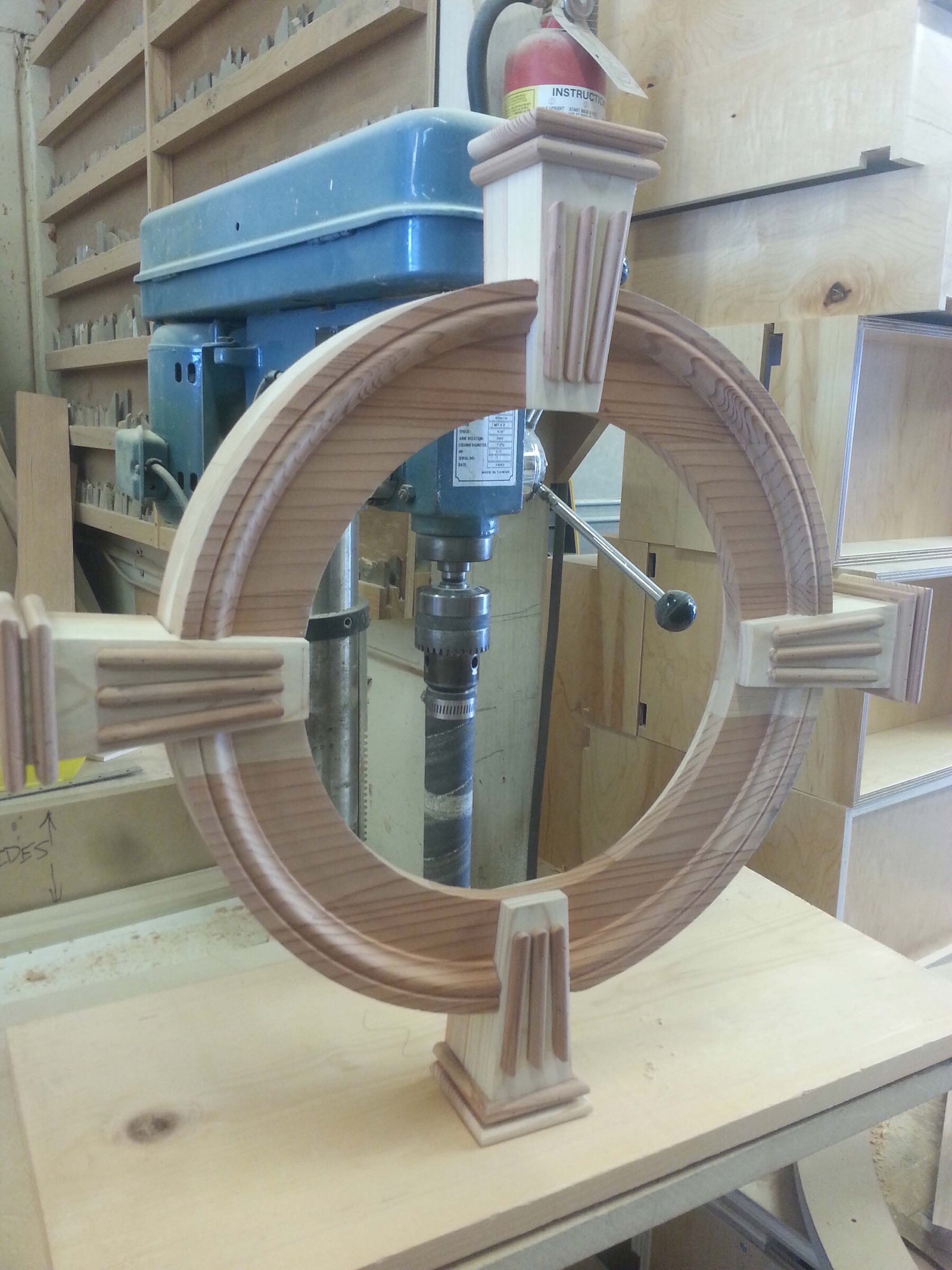 Custom round wood window frame with fluted keystone corner blocks being fabricated on a drill press in the workshop